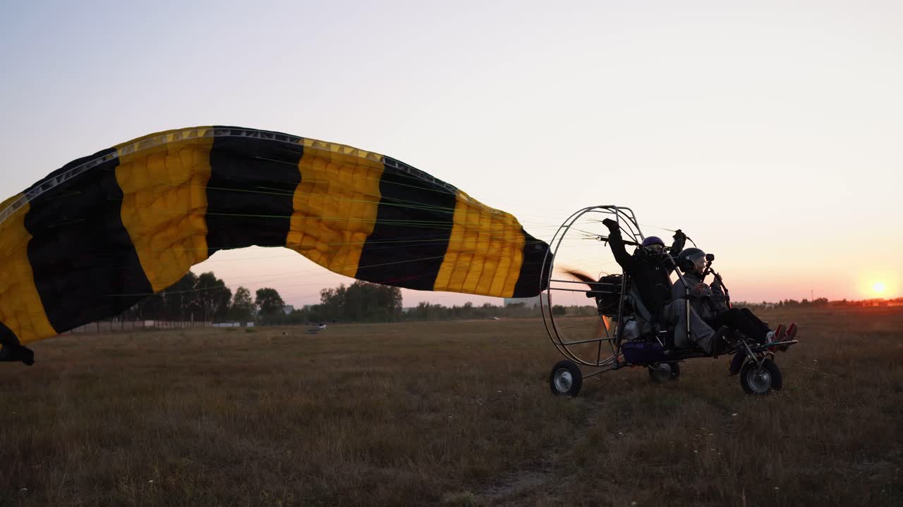 el parapente de motor despegue con una chica y un hombre en el aeropuerto acelerando y despegando en el cielo en paracaídas.