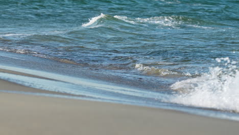 gentle waves lapping at the beach, with the clear water reflecting the sunlight in a serene setting