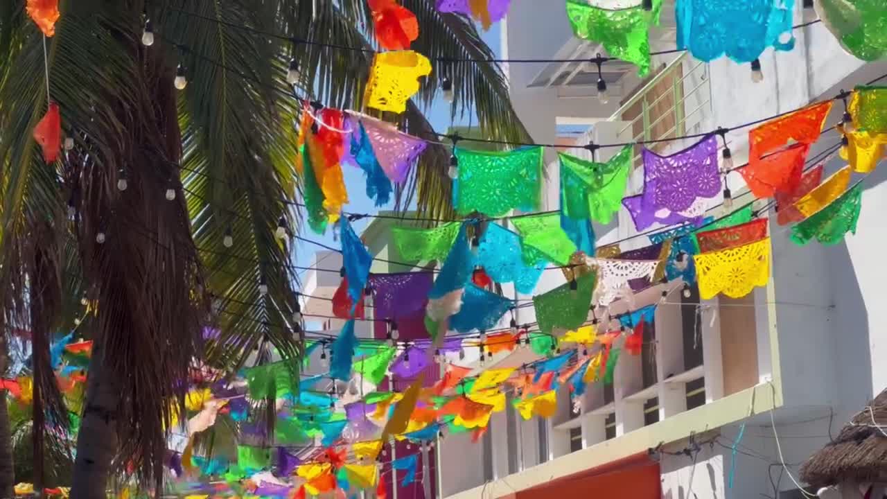Handheld panning shot of colorful flags lining the street in Playa del Carmen, Mexico. 4K at 30 FPS