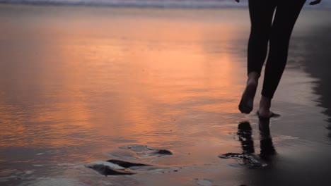 Mujer-Descalza-En-Polainas-Camina-Hacia-El-Océano-Al-Atardecer,-Playa-De-Azores