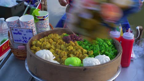 close up of a large container of thai vegetables which the vendor delivers to the customer in plastic bags