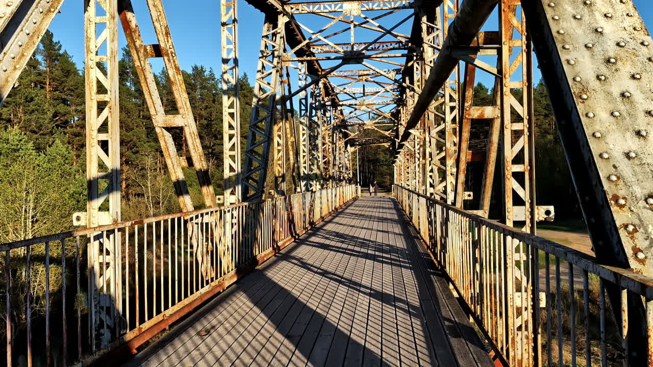 Metal truss bridge walkway in evening light with forest view on golden hour