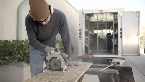 carpenter using circular saw to cut wood plank or board outside