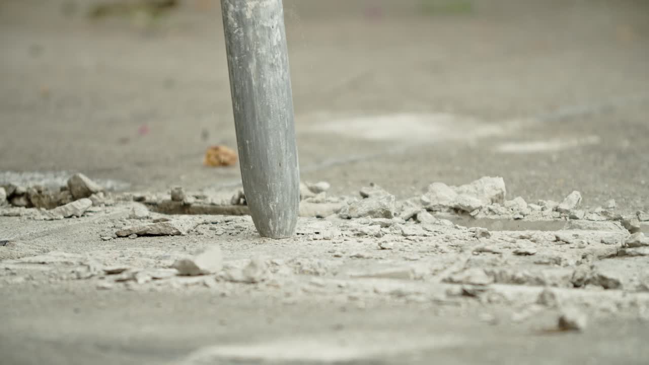Close-up of excavator hydraulic arm rock breaker working on concrete road with sound