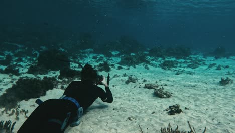 marine biologist on ocean floor with camera capturing aquatic life