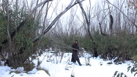 a bushman carrying wood in the snow in the mountains of australia