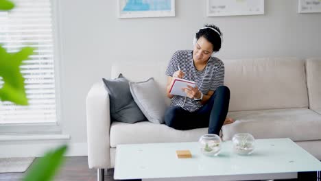 Woman-writing-in-book-while-listening-to-music-4k