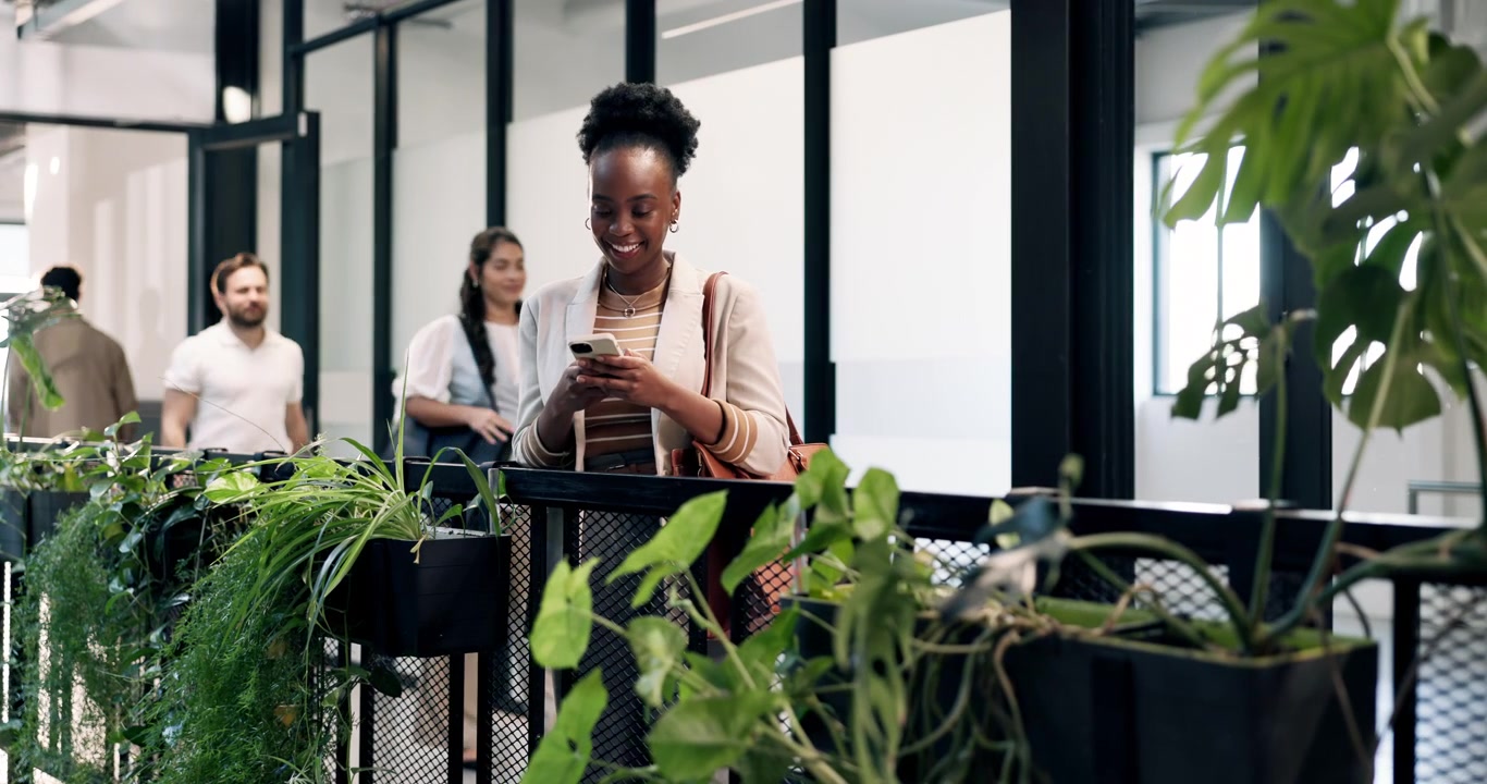 Young Woman Using Smartphone in Modern Office Hallway