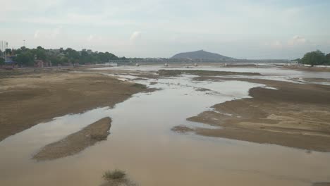 wide view of dry riverbed with leftover water in summer heat weather, bodhgaya, bihar, india