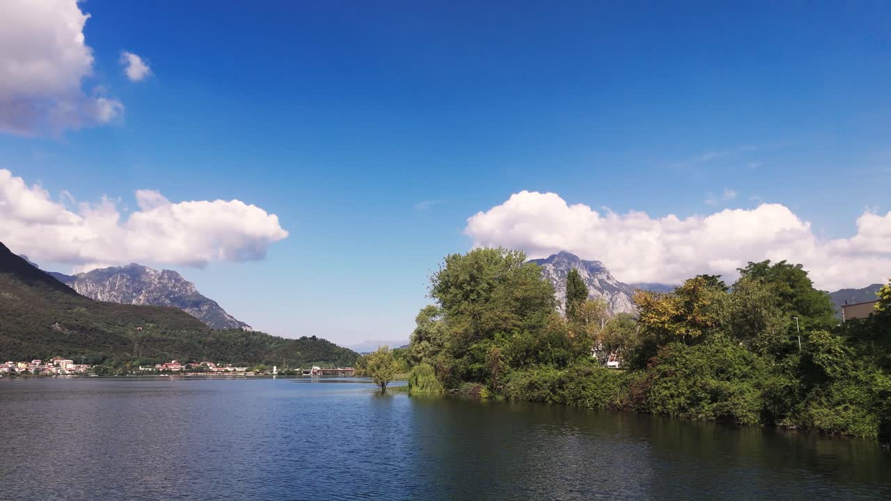 Fly over Lake Garlate next to land and trees, Italy