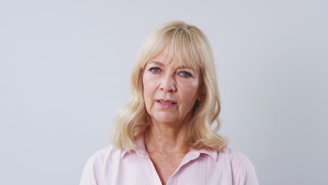 studio shot of unhappy and frustrated mature woman against white background at camera