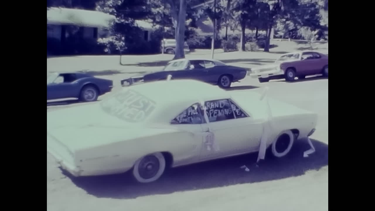 Man Standing Next to White Car in Parking Lot During 1970s in USA. CIRCA USA - 1970s: A man stands next to a white car in a parking lot, captured in this archive video from the 1970s in the USA.