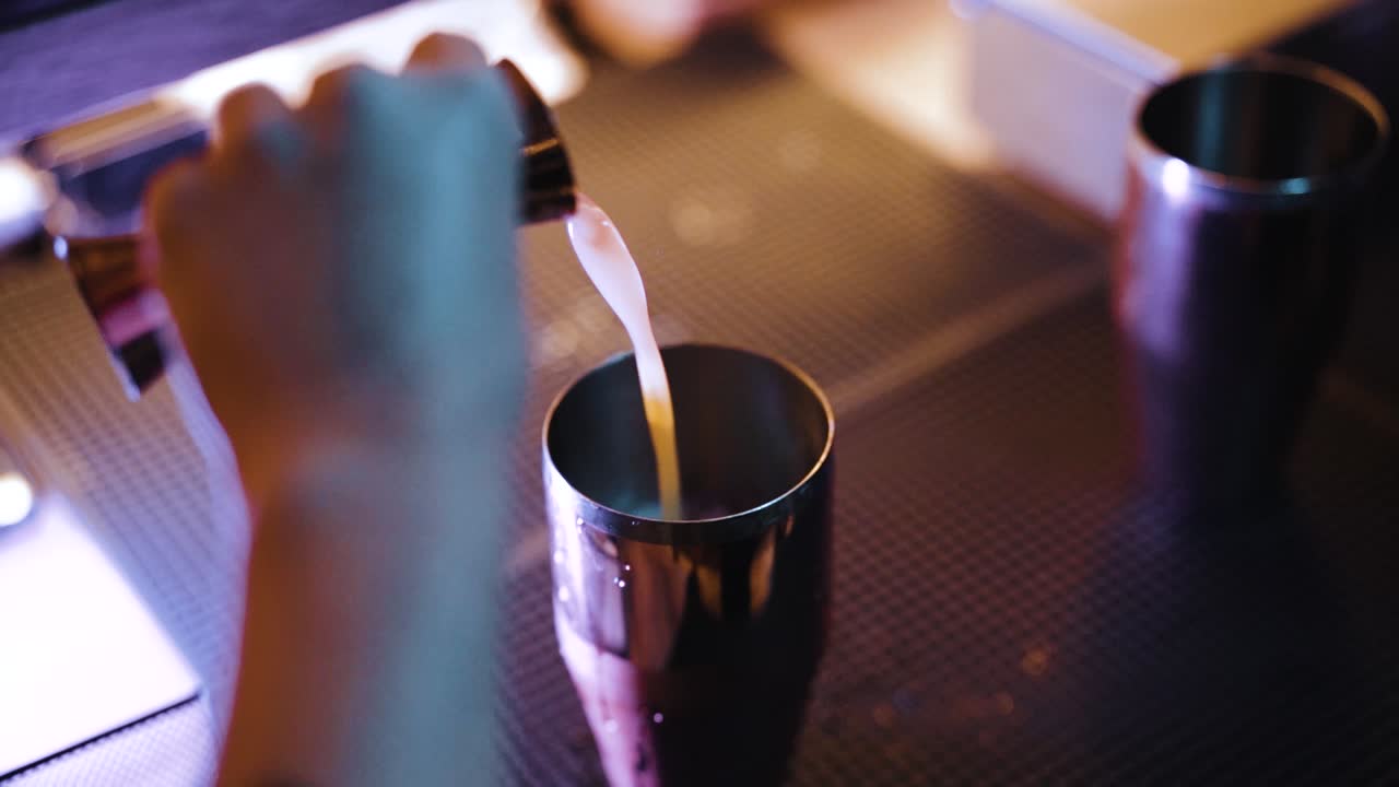 Mano tatuata di un barista che prepara shot colorati al rallentatore