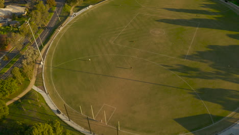 Mehrere-Gruppen-Von-Menschen-Nutzen-Den-Leeren-Sportplatz,-Um-Die-Nachmittagssonne-Zu-Genießen