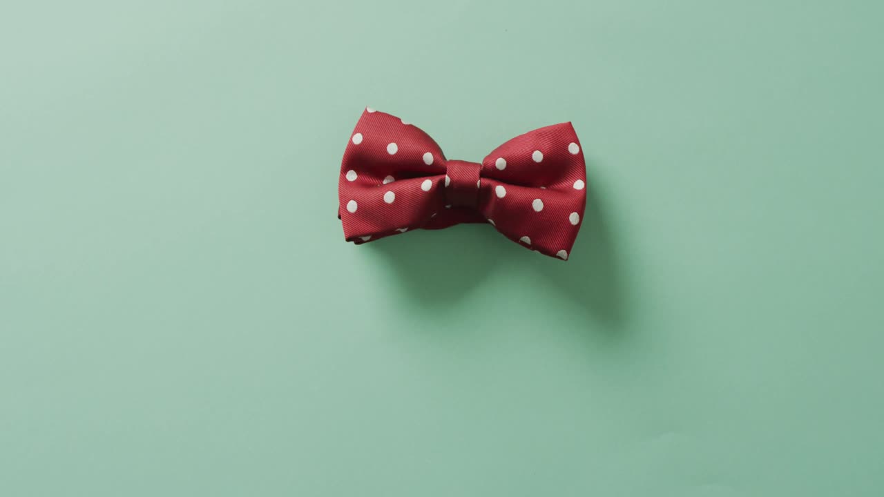 Video of red dotted bow tie lying on green background