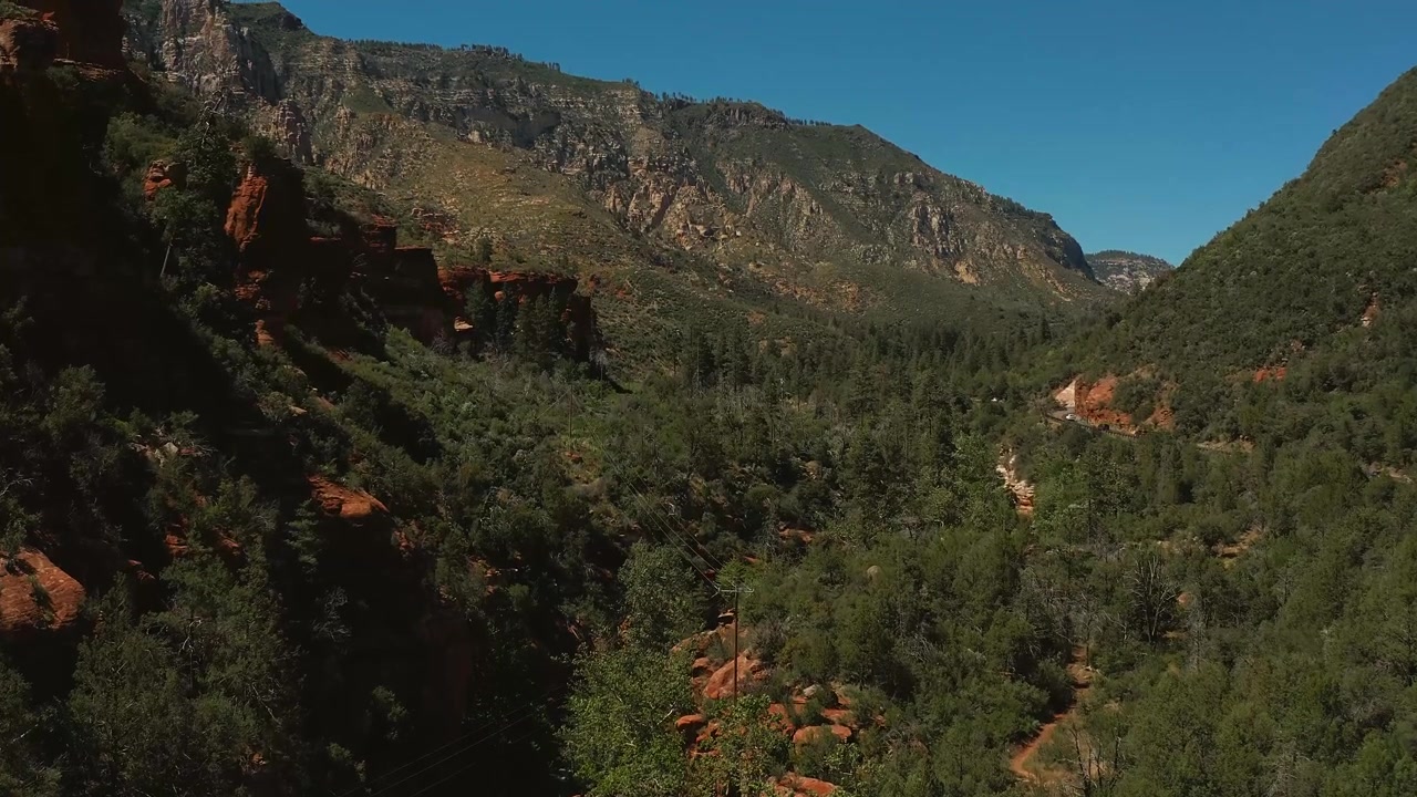 Toma cinematográfica de ascenso lento que revela gradualmente la impresionante cordillera de Sedona en el Parque Estatal Slide Rock, Arizona.
