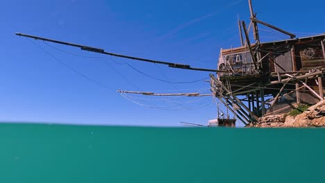 Half-underwater-view-of-trabocco-or-trabucco-at-Punta-Penna-beach-in-Costa-dei-Trabocchi-,-Abruzzo-in-Italy