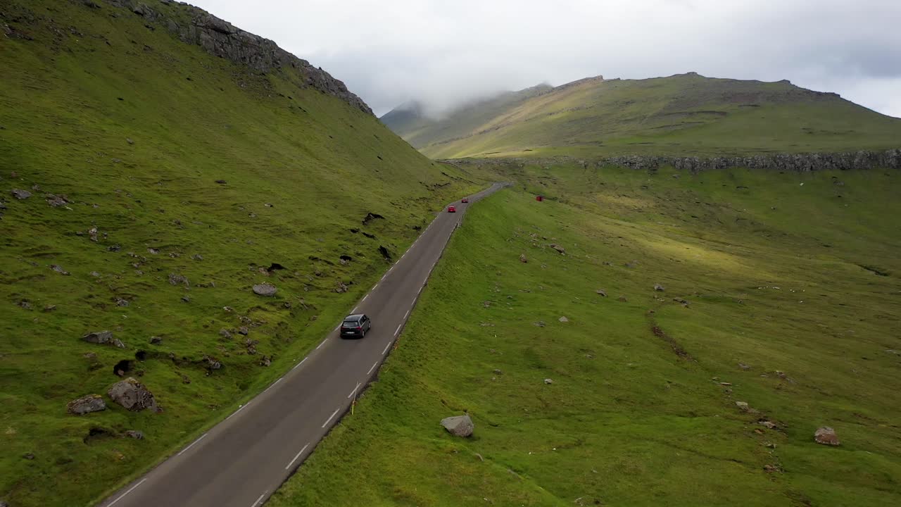 멀리 떨어진 페로 섬의 시골 도로를 따라 자동차를 따라 비행
