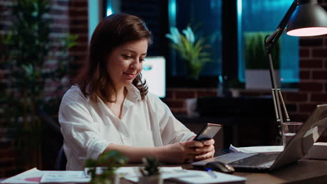 Smiling-manager-looking-at-text-messages-on-smartphone,-taking-break