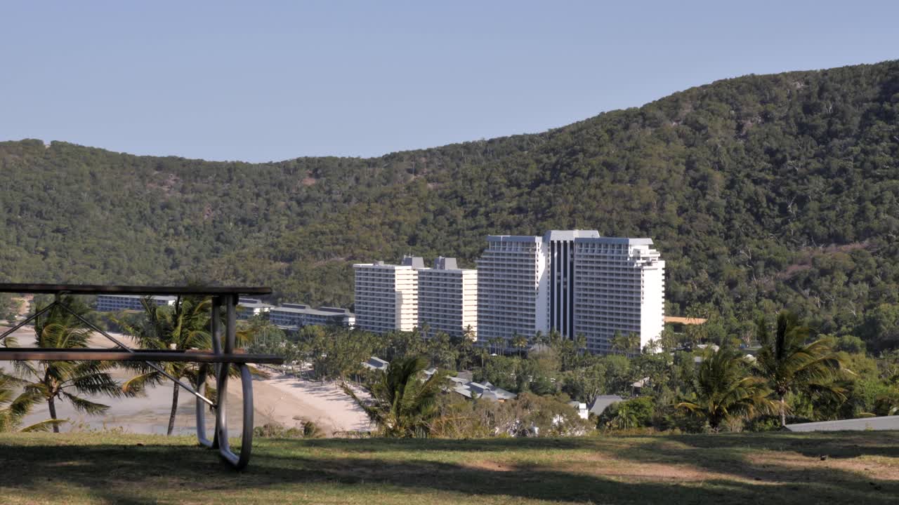 호주 즐랜드의 해밀턴 섬에 있는 세이 해변을 내려다보는 멋진 풍경 - 멋진 빛의 여름날에 배경에 큰  건물이 있습니다.