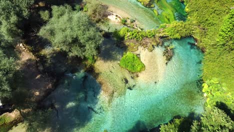 drone shot of the blue eye in albania - drone is flying over the river, ending at the actual blue eye, the river source