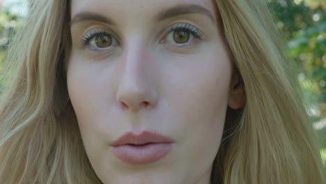 close up of an attractive young woman with blonde hair, talking confidently to the camera