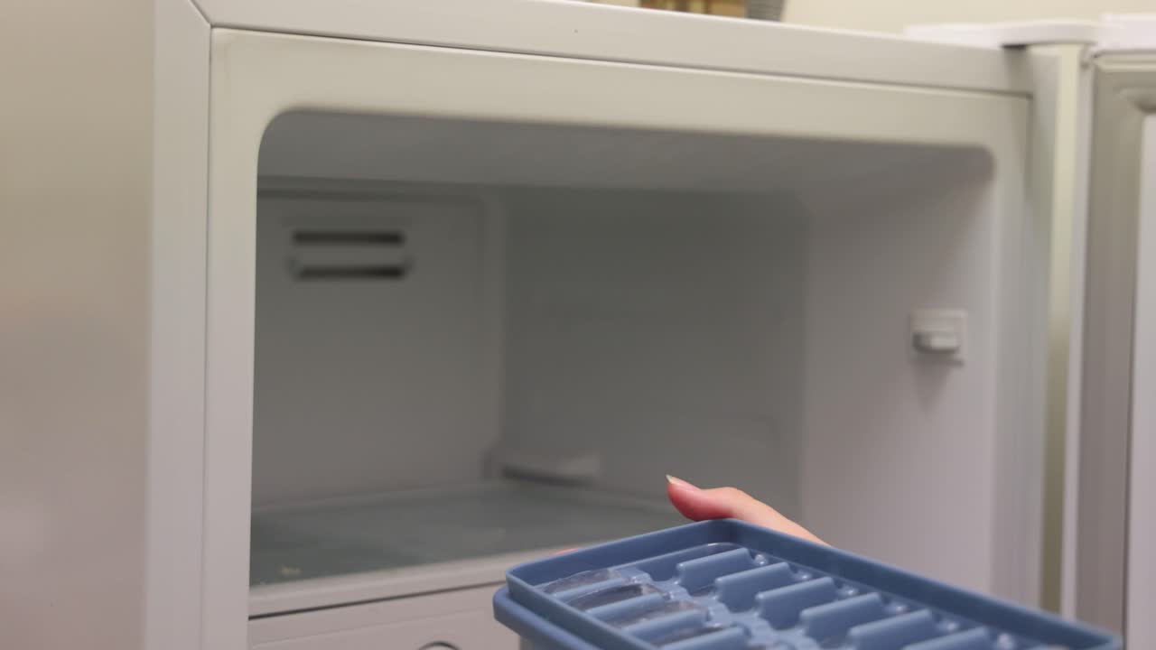 persona saca la bandeja de hielo del congelador