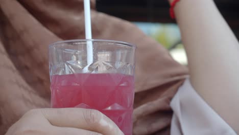a person drinking a pink beverage from a glass with a straw