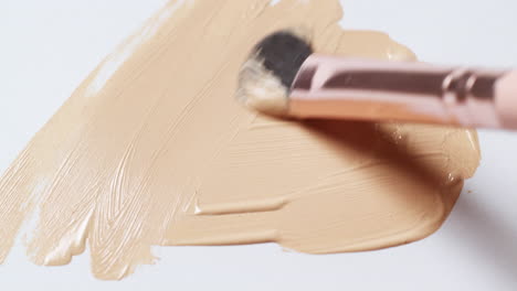 brushing a layer of make-up foundation on a clean, white palette board to check its texture and tone