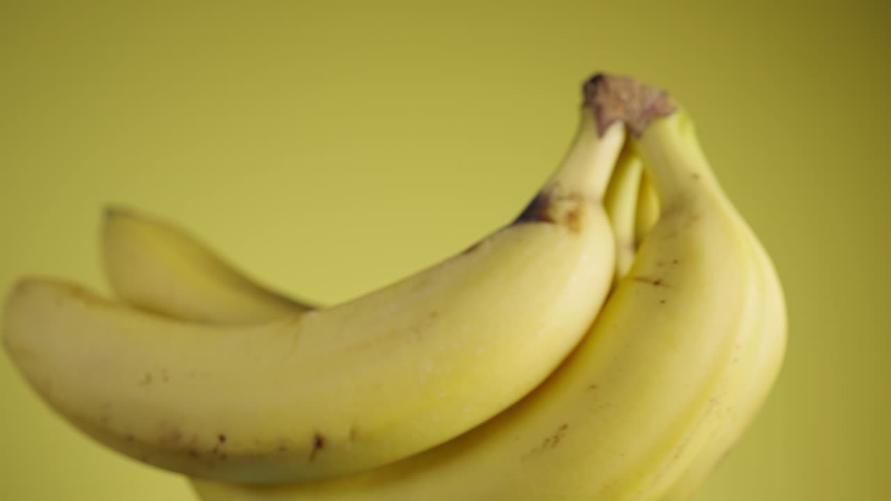 노란색 은 바나나는 노란색 배경에 천천히 회전하고 있습니다.