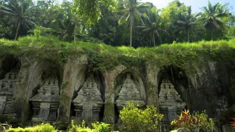 Tiro-Inclinado-Hacia-Arriba-De-Las-Ruinas-Históricas-De-Un-Templo-En-Bali,-Indonesia,-Con-Una-Fuente-Y-Vista-De-La-Densa-Jungla