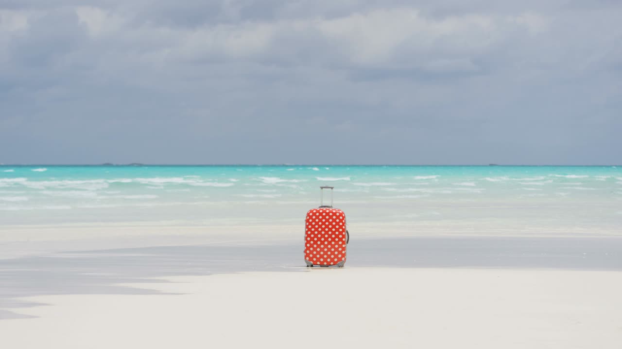 모래 해변 에 있는 다채로운 여행 가방