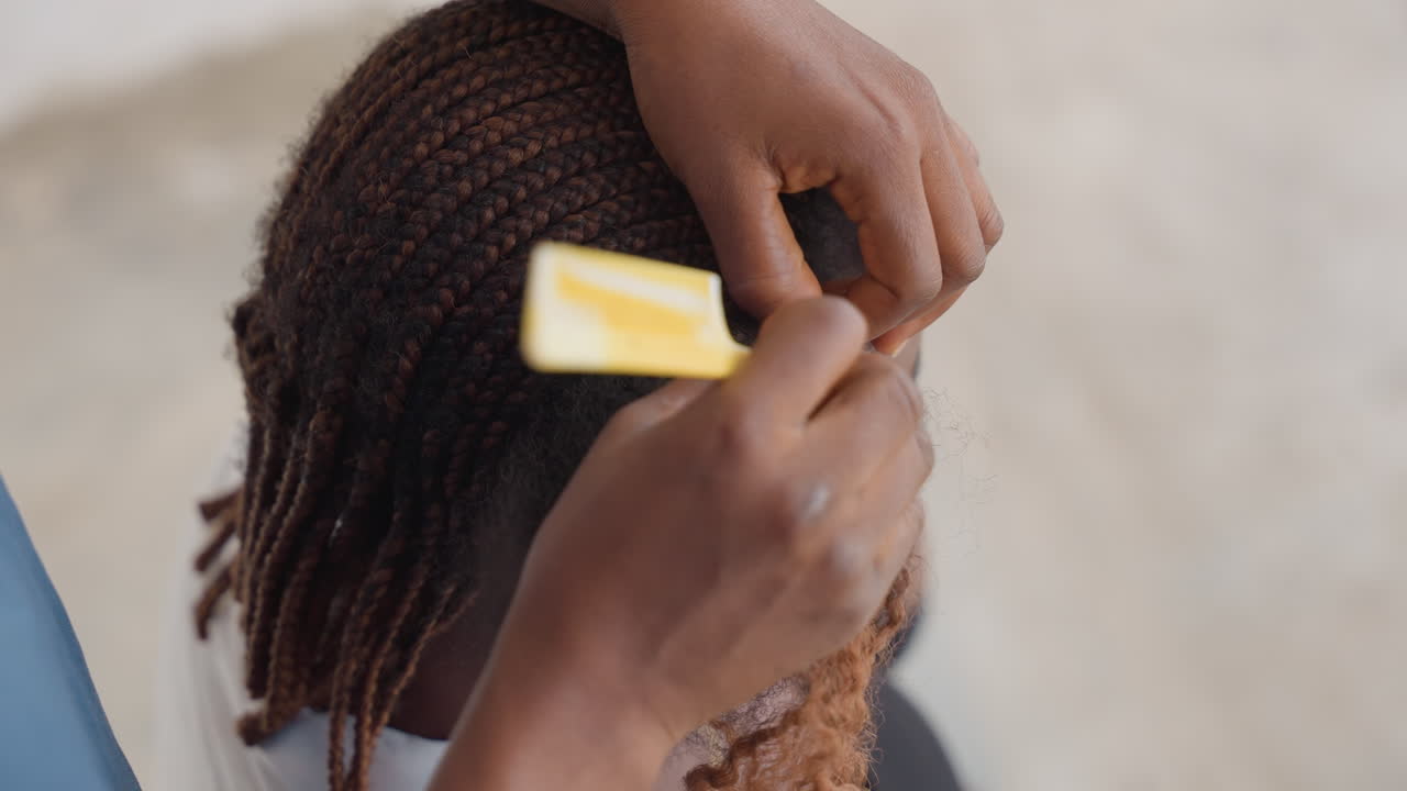 Closeup black braider finishing cornrows with precision, comb aligning neat rows, textured ends blended, focused hands, salon atmosphere, symmetry and craft highlighted, cultural artistry