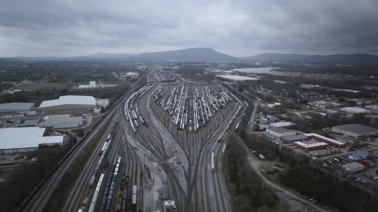 Aerial drone timelapse of the giant trainyard in Chattanooga, TN on a cloudy day with Lookout Mountain the background and many trains moving.