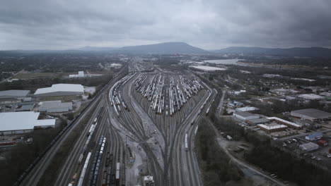 aerial drone timelapse of the giant trainyard in chattanooga, tn on a cloudy day with lookout mountain the background and many trains moving.