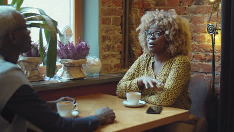 black man and woman having coffee and speaking in cafe