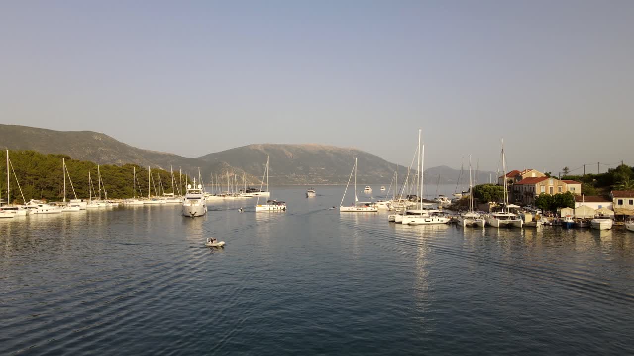 Panoramico tramonto estivo serale nella città costiera di Fiskardo, Grecia, carrellata aerea in avanti.