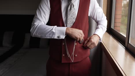 close up groom in formal vest holding vintage pocket watch by window light