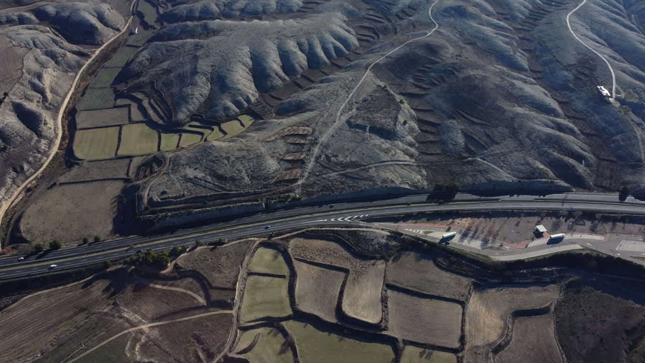 Aerial view of a highway and terraced fields in a mountainous landscape