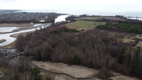 Drone-Dando-Vueltas-Sobre-Campos-De-Invierno-Cerca-De-Un-Río-Congelado-En-Ajax