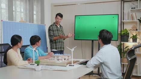 un ingeniero asiático con celdas solares tiene éxito presentando sobre la televisión de pantalla verde en la oficina, la audiencia aplaude y se siente impresionado