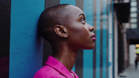 profile portrait of a young woman in pink against an urban striped wall