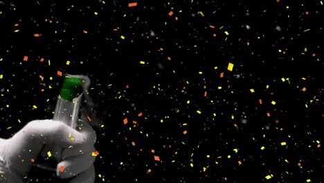 confetti falling over mid section of person opening a champagne bottle against black background