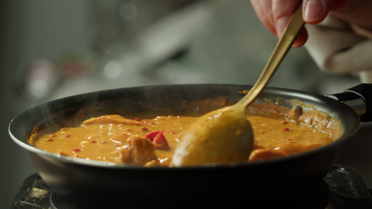 Yellow boiling sauce on pan close-up. Asian cuisine concept. Curry is a dish with a sauce seasoned with spices. Curries may contain fish, meat, poultry, or shellfish, either alone or in combination with vegetables. Others are vegetarian.