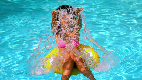 Mujer-Feliz-En-Bikini-Rosa-Divirtiéndose-En-Un-Anillo-Inflable-En-La-Piscina