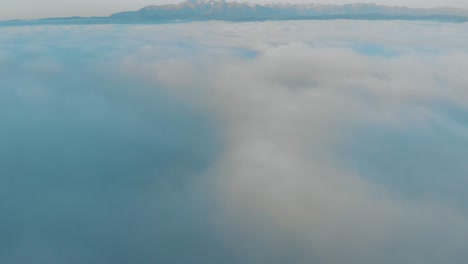 高山慢慢地露出在厚厚的云层上方, 太阳升起后, 蓝色的天空