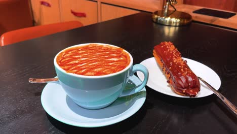 de una gran taza de café con leche de caramelo y chocolate eclair disparado en una mesa en un café