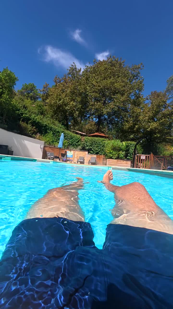 Set fra en person, der flyder og slapper af i en blå swimmingpool