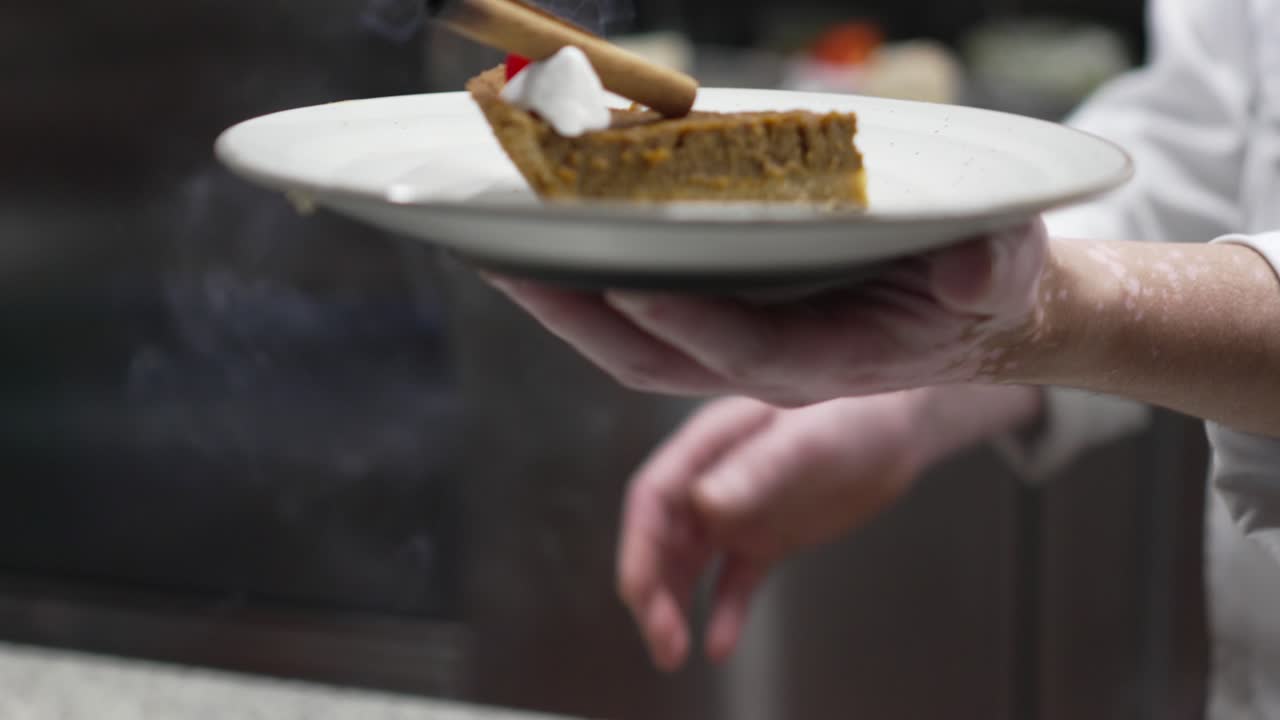 el chef de pastelería prepara una rebanada de pastel de crema de brownie de calabaza con canela y cereza