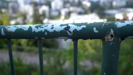 A-very-old-green-iron-fence-with-peeling-paint,-Rusty-iron-railings-on-view-of-Haifa,-Israel